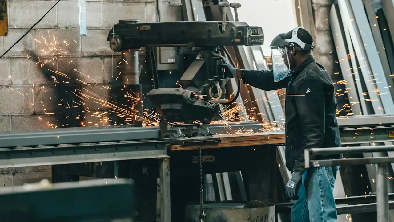 A man wearing protective gear works on a machine in a factory