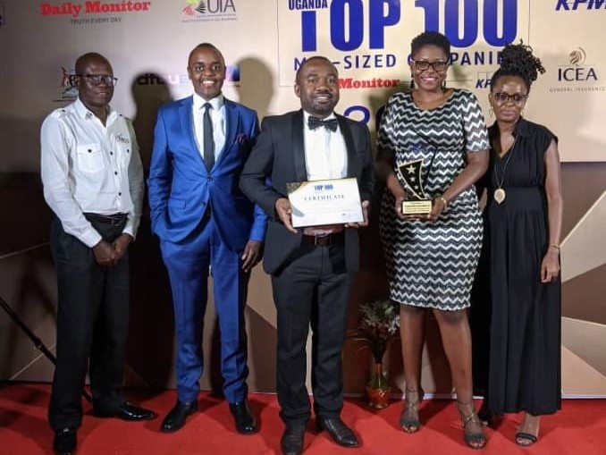 A group of five people posing with a certificate and a trophy at a gala dinner